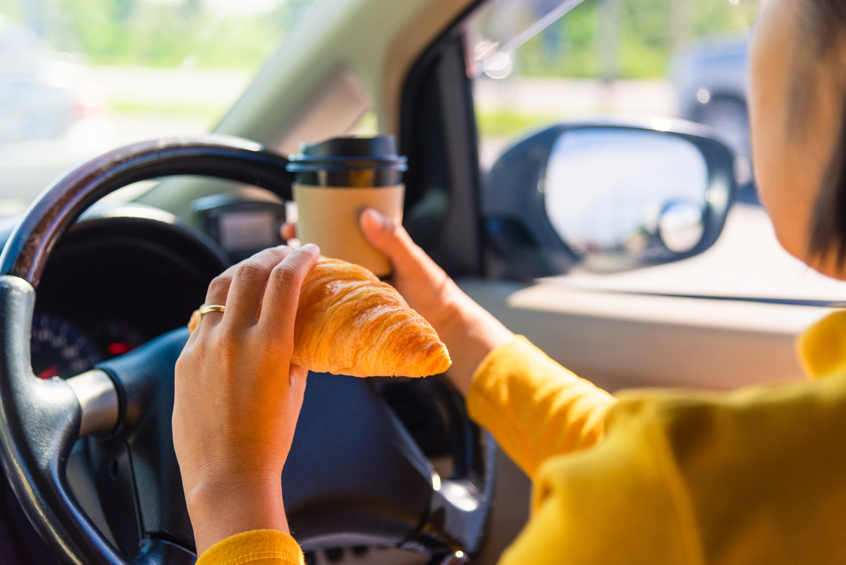 Le Code de la route n'interdit pas formellement de boire et manger au volant, mais vous pouvez être verbalisé pour défaut de maîtrise du véhicule. Crédit photo : Shutterstock - Mondial de l'Auto 2022