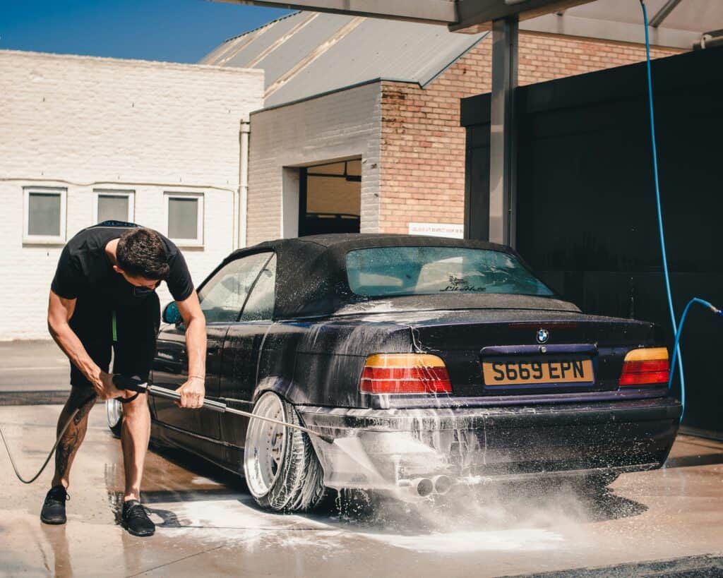 Un homme lavant au jet d'eau puissant sa voiture