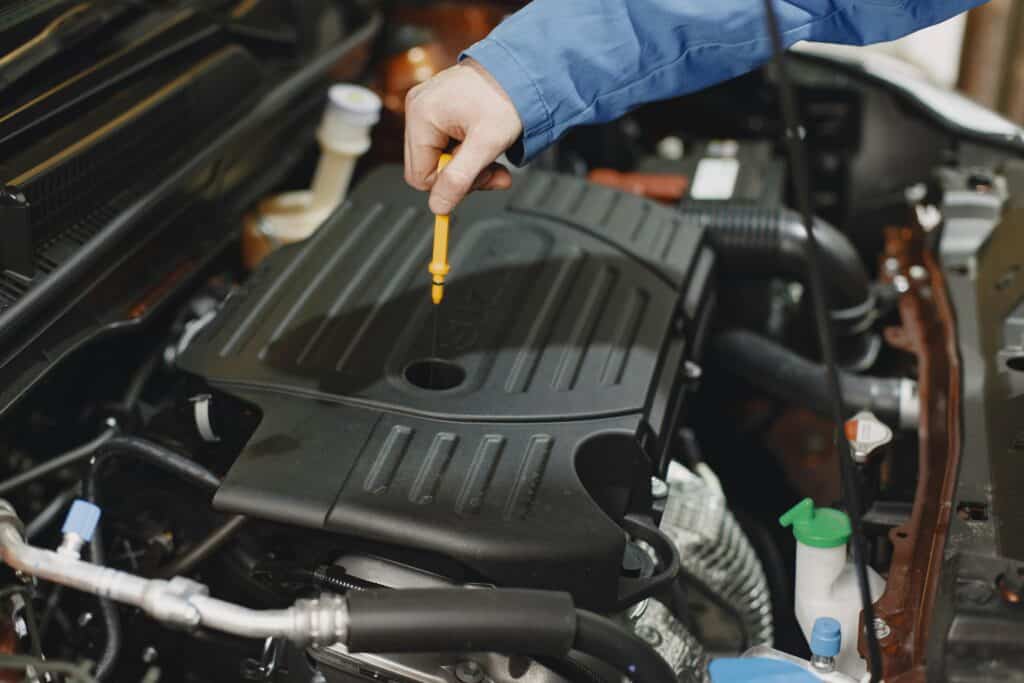 Mécanicien ouvrant le réservoir d'huile moteur - changement huile moteur voiture diesel - mondial de l'auto 2024