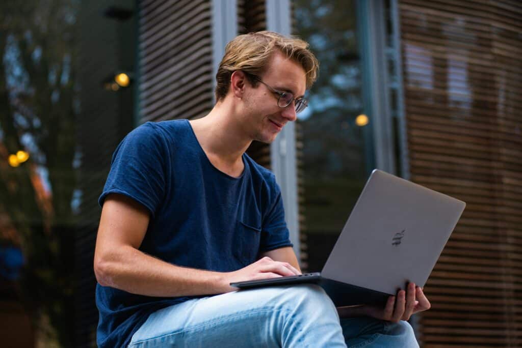 homme devant un ordinateur qui fait une recheche sur internet pour vérifier comment changer les bougies d'allumage soi-même / mondial de l'auto 2024