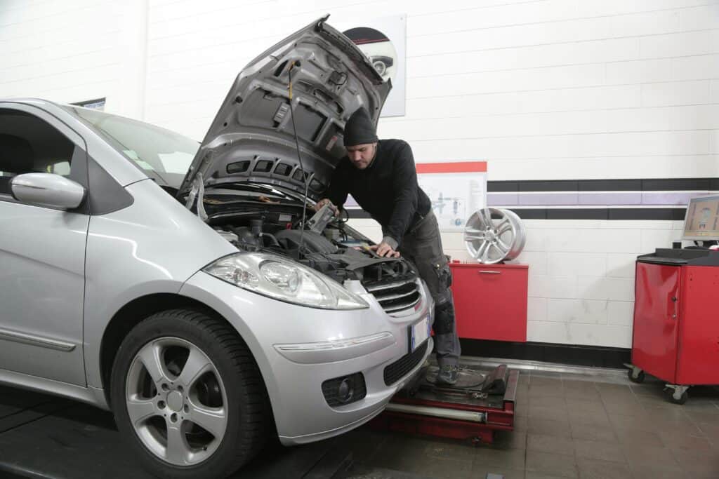 garagiste qui procède au changement des bougies d'allumage d'une voiture - mondial de l'auto 2024