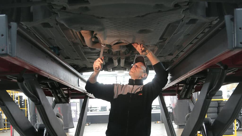 mondial de l'auto - photo d'un garagiste sous une voiture entrain de faire des réparations - embrayage 