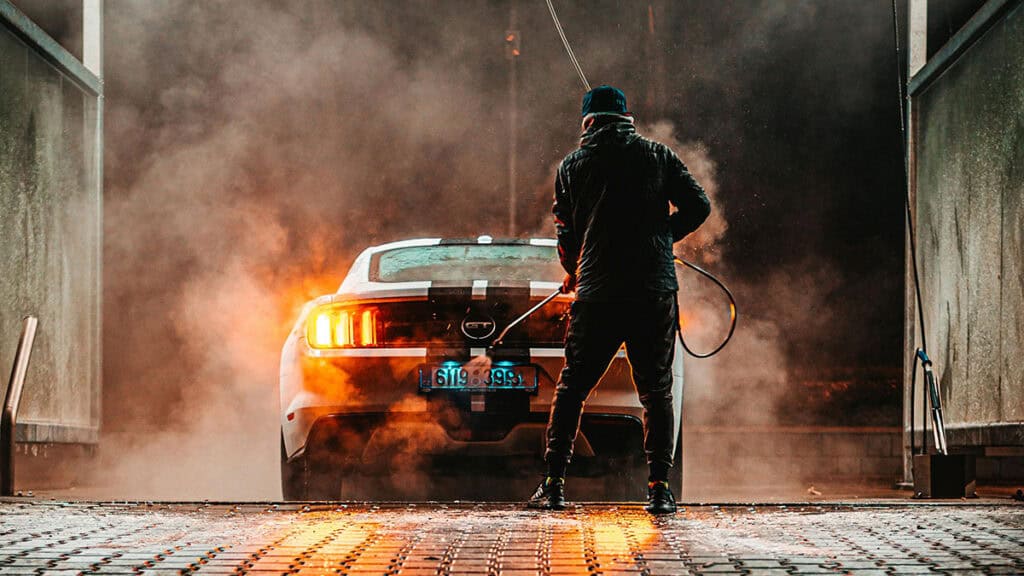 photo d'un homme de dos dans une station de lavage, avec un jet de lavage haute pression a la main, entrain de laver a voiture - mondial de l'auto 2026