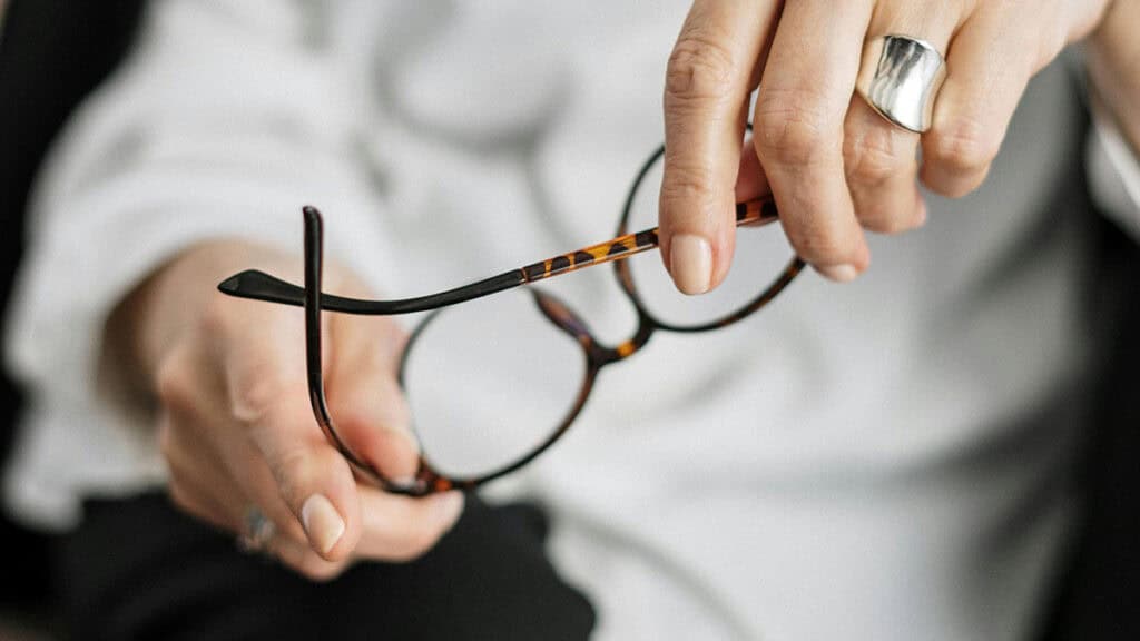 femme tenant une paire de lunette à la main - assurance et port de lunettes au volant conduire sans ses lunettes - mondial de l'auto 2026