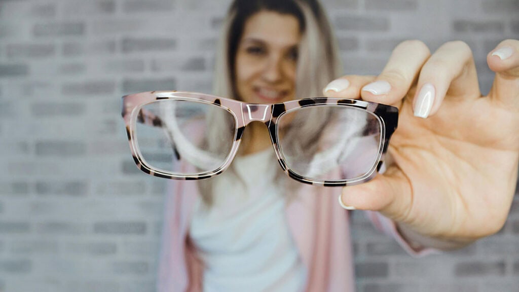 gros plan d'une femme montrant ses lunettes de vue qu'elle tient à la main - assurance et port de lunette de vue obligations - mondial de l'auto 2026