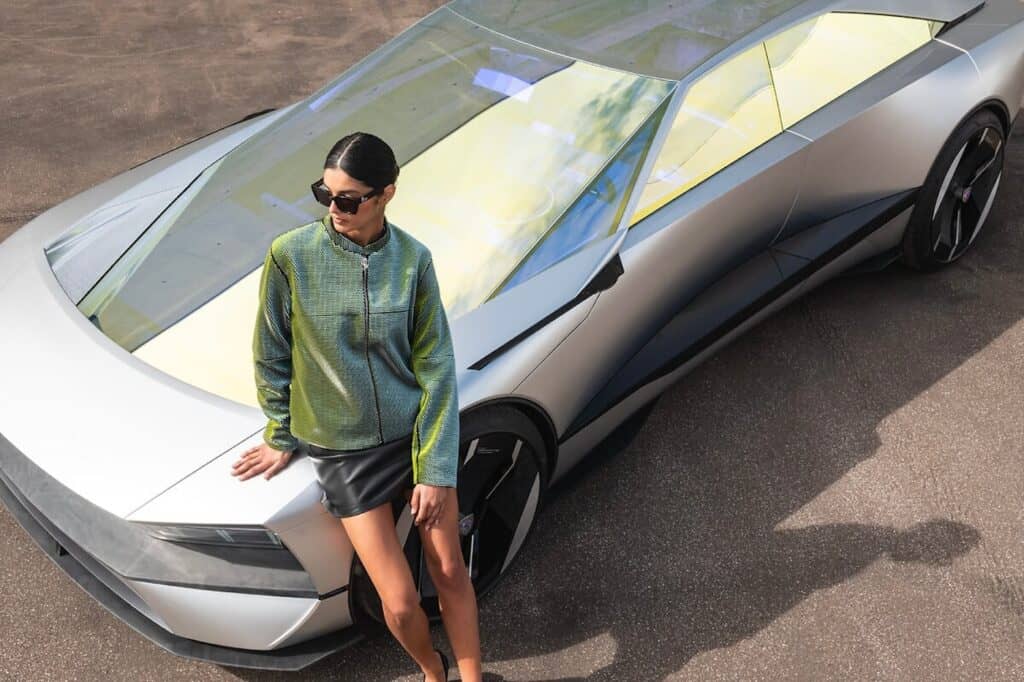 intention concept peugeot - mondial de l'auto 2024 - stellantis - photo d'une femme assise sur l'avant de la voiture 