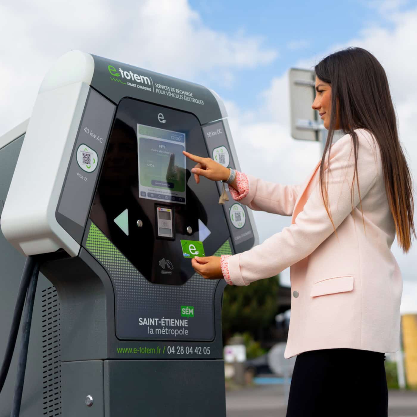 photo d'une dame entrain d'utiliser une borne de recharge pour voiture eelctrique e-totem - mondial de l'auto 2024