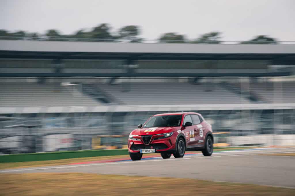 photo de l'alfa romeo junior ellectrica sur circuit - plan sur route de la voiture vue de 3/4 coté - mondial de l'auto 2026